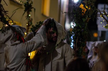 Canlı bir İspanyol Cadılar Bayramı karnavalı sırasında pelerinli ve folklorlu insanların atmosferik gece çekimleri. Şenlik havası, yerel gelenek, kültürel kutlama.