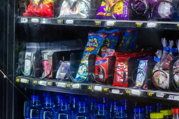 Abur cubur ve şişe suyla dolu parlak ışıklı otomat, ofisler, okullar veya istasyonlar gibi kamusal alanlarda hızlı içecekler için ideal.