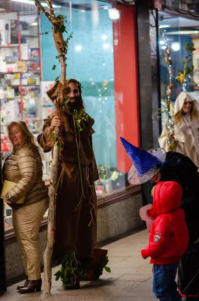 İspanyol Cadılar Bayramı karnavalındaki atmosferik akşam sokak sahnesinde yetişkinler ve çocuklar fantezi kostümleriyle şenlik kutlamalarının keyfini çıkarıyorlar..