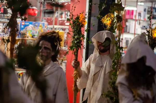 Beyaz kapüşonlu kostümler ve dramatik yüz boyama yürüyüşü katılımcıları canlı bir İspanyol Cadılar Bayramı karnavalı geçit töreninde ellerinde dekoratif kadro ve festival sokak kültürünü kucaklıyorlar..