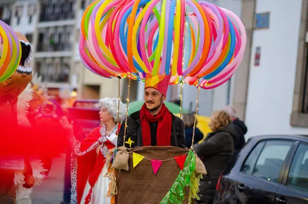 Canlı, sıcak hava balonu kostümlü yaratıcı bir adam renkli balonlarla şehir sokaklarında şenlikli bir karnaval boyunca yürür, neşe ve eğlence yayar..