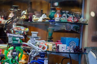 Renkli hookahlar ve geleneksel doğu hatıraları bir market vitrinindeki cam raflarda sergilenerek turistler ve yerel halk için canlı bir Orta Doğu atmosferi yaratıyor..