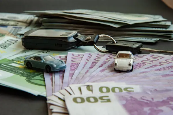 Business concept, car insurance, sell and buy car, car financing. Euro and dollar banknotes on the table, model cars and car keys