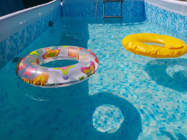 Yellow pool float, pool ring in cool blue refreshing blue pool. Filling the pool with water The beginning of the bathing season in the pool