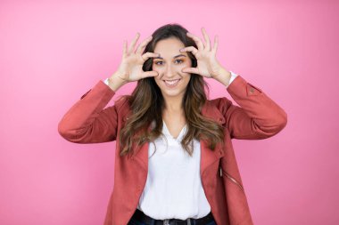 İzole edilmiş pembe arka planda rahat ceket giyen genç ve güzel bir kadın gözlerini parmaklarıyla açmaya çalışıyor, uykulu ve yorgun bir şekilde sabahları yorgunluk çekiyor.