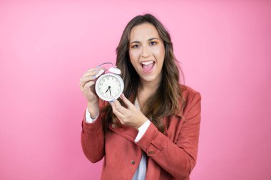 İzole edilmiş pembe arka planda rahat ceket giyen genç ve güzel bir kadın.