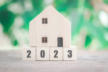 Yeni yıl mülkü. Ahşap ev modeli, ahşap blok numarası 2023 ve arka plan konsepti olarak ev, iş, gayrimenkul ve mülkiyet kavramını satın almada tasarruf etmek için alanı kopyalamak..