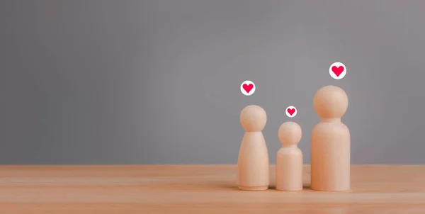Concept for family relationship, family home, foster care, homeless charity support, family mental health, international day of families with wooden figures peg doll of family members on wood table.