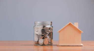 Full of coins in a glass jar and house model concept for saving money, step to keep money for new home, prepare money and future success.