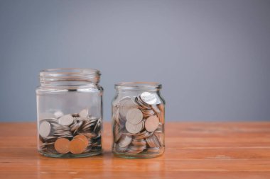 Money in the glass jar on wooden table with filter effect retro vintage style. Save money concept for Finance Banking Business Ideas, Investments, Funds, Bonds, Dividends and Interest.