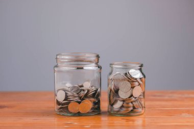 Money in the glass jar on wooden table with filter effect retro vintage style. Save money concept for Finance Banking Business Ideas, Investments, Funds, Bonds, Dividends and Interest.