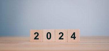 2023 'ten 2024' e. Mutlu Noeller ve mutlu yıllar, ahşap küp bloklardaki numaralar kopya alanı olan ahşap masa. 2024 Yeni Yıl Fikri.