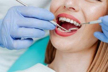 Diş sağlığı kliniğinde beyaz dişli çekici bir genç kadın. Tıbbi aletlerle el doktoru diş hekimi. Sağlıklı diş konsepti