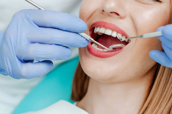 stock image Attractive young woman with natural white teeth in dental clinic. Hands doctor dentist with medical tools. Healthy teeth concept