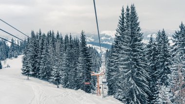 Kayak asansörü ya da karlı orman manzarasında füniküler. Karla kaplı köknar ağaçları olan donmuş dağların panoramik manzarası. Kış tatili ve kayak merkezinde dinlenme