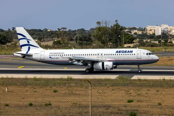 Luqa, Malta - 30 Haziran 2024: Ege Havayolları Airbus A320-232 (REG: SX-DVT) hala eski renk şemasında.