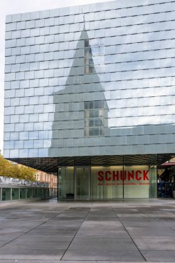 Heerlen, Netherlands - October 26, 2024: St. Pancras Roman Catholic church reflected in the Schunk art building, a venue for contemporary art and architecture clipart