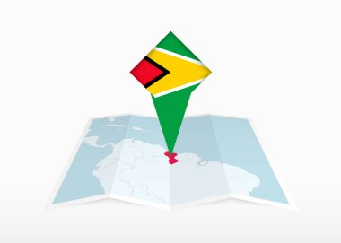 Guyana katlanmış bir kağıt haritada resmedilmiş ve Guyana bayrağıyla işaretlenmiş..