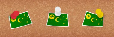Cocos Adaları bayrağı mantar panoya asılmış, Cocos Adaları bayrağının üç versiyonu.