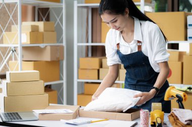 Online iş için kutu paketleyen genç bir kadın, çevrimiçi satışlar, paket teslimatı, e-ticaret.