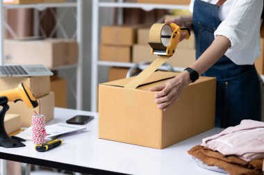 Çevrimiçi iş teslimatı, çevrimiçi satış, paket teslimatı, e-ticaret için maskeleme bandı olan genç bir kadın..