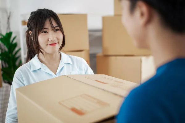 Young couple with big boxes moving into a new house, new apartment for couple, young man and woman helping to lift boxes and organize things for the new home, Moving house.