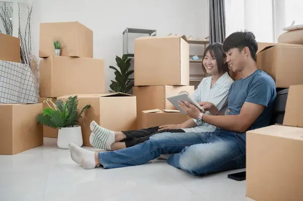 Young couple with big boxes moving into a new house, new apartment for couple, young man and woman helping to lift boxes and organize things for the new home, Moving house.