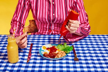 Klasik kıyafetler giyen, salata ve portakal suyuyla sandviç yemeye hazır genç bir kadının yaratıcı portresi. Antika, retro tarzı iç mekan. Mavi, kırmızı ve sarı. Sürrealizm