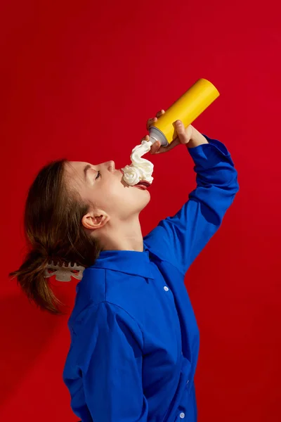 奇妙な人々の概念 ヴィンテージの赤を背景にした甘いホイップクリームを味わう若い女の子 創造性 カラフルなミニマリズム 広告の概念 相補的な色 — ストック写真