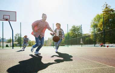 Üç genç okuldan sonra basketbol topuyla sokak basketbolu oynuyor. Spor, eğlence aktiviteleri, hobiler, takım, arkadaşlık. Erkekler ve kızlar birlikte vakit geçiriyorlar..