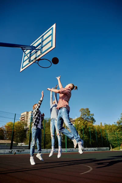 Leisure games. Group of friends bonding outdoors to play street basketball. Teens wearing casual style clothes. Look happy, delighted. Social gathering, friendship, team and happy childhood