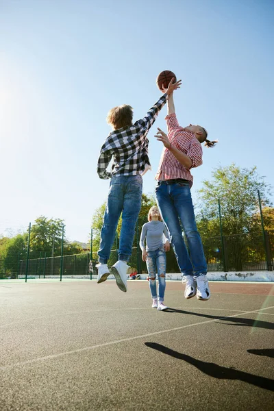 若い男の子と女の子は 学生の屋外の通りのバスケットボールをプレイする結合 10代はカジュアルなスタイルの服を着て 幸せそうだな 社会的な集まり チームと幸せな子供時代 — ストック写真
