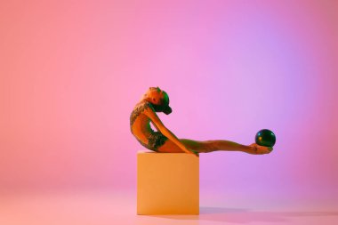 Güzel ve esnek zarif sporcu ritmik jimnastik sanatçısı dans ediyor, renkli arka planda izole edilmiş esneme egzersizleri yapıyor. Güzellik, sanat, spor, rekabet, reklam ve hobiler