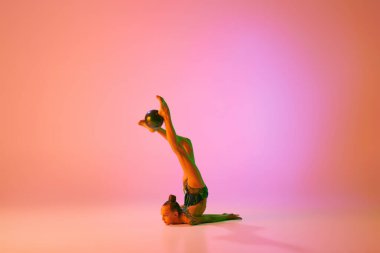 Her zamanki gibi. Genç esnek genç kız ritmik jimnastikçi, pembe arka planda izole edilmiş hareket neon ışığı altında. Spor, güzellik, rekabet, esneklik, aktif yaşam tarzı. Bireysel