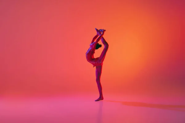 伸直了年轻柔韧的少女节奏体操运动员在运动中 动作孤立在粉红背景的霓虹灯下 灵活性 积极的生活方式 个人业绩 — 图库照片