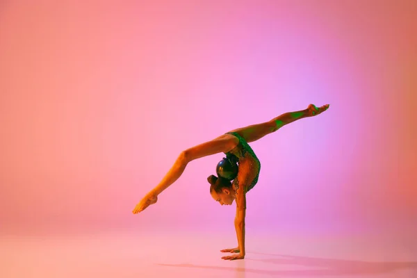 手倒立年轻柔韧的少女节奏体操运动员在运动中 动作孤立在粉红背景的霓虹灯下 灵活性 积极的生活方式 个人业绩 — 图库照片