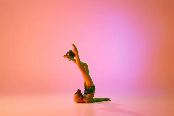 ボールでルーチン 運動中の若い柔軟な10代の少女リズム体操 ネオンの光のピンクの背景に隔離されたアクション スポーツ 美しさ 柔軟性 アクティブなライフスタイル — ストック写真
