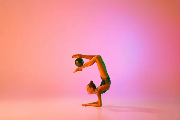 若い魅力的な女の子のスタジオショット ネオンライトフィルターでピンクの背景に隔離されたスポーツ機器とリズミカルな体操トレーニング ダンス モチベーション — ストック写真