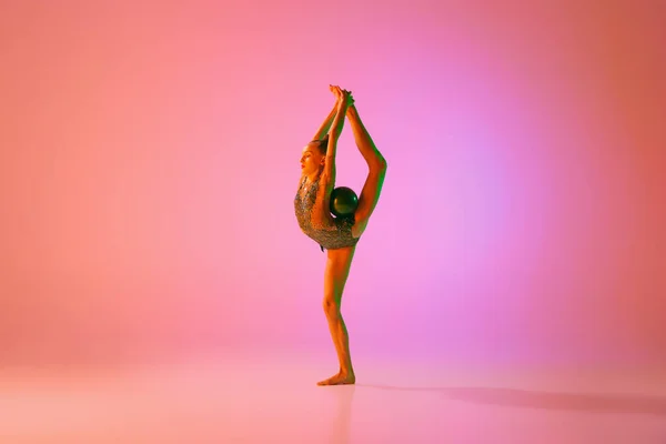 年轻柔韧的少女节奏体操运动员在运动中 动作孤立在粉红背景的霓虹灯下 灵活性 积极的生活方式 个人业绩 — 图库照片