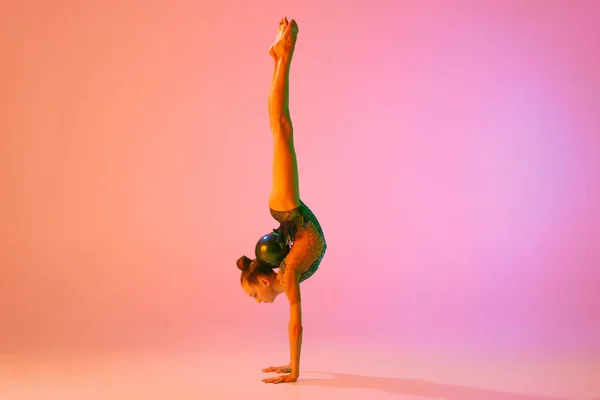 若い魅力的な女の子のスタジオショット ネオンライトフィルターでピンクの背景に隔離されたスポーツ機器とリズミカルな体操トレーニング ダンス モチベーション — ストック写真