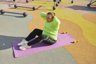 Açık hava eğitimi. Kilo kaybı konsepti. Sokak sporları sahasında spor yapan genç bir kadın. Güneşli bir sonbahar günü. Sağlık, spor, sağlık, ruh hali, beden pozitifliği kavramı