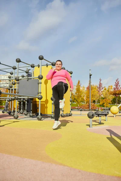 Outdoor training. Weight lost concept. Young woman doing fitness exercises at street public sports ground. Sunny autumn day. Concept of wellness, sport, health, mood, body positive