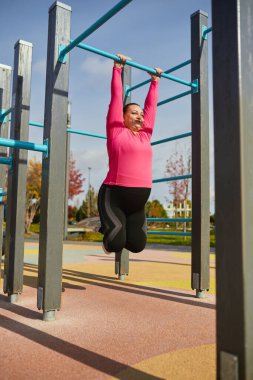 Pozitif tutum en iyi sonucu elde etmek için yardımcı olacaktır. Enerjik obez genç kadın, baharda güneşli bir günde spor salonunda spor giyim antrenmanı yapıyor. Meydan okumalar, hayaller, fitness, sağlıklı