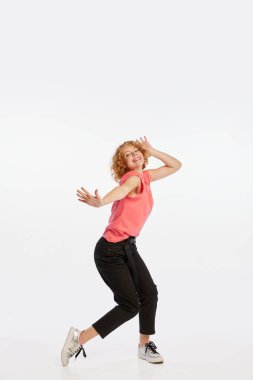 Mutluluk, müzik. Beyaz stüdyo arka planında yalnız dans eden heyecanlı, genç, kızıl saçlı bir kadın. İnsani duygular, yüz ifadesi, güzellik konsepti. İlan için alanı kopyala