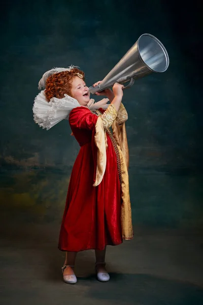 一个红头发的小女孩的画像 一个穿王室服装的孩子 用深绿色背景隔离的扩音器大喊 历史重制的概念 中世纪时尚 女王的比较 — 图库照片