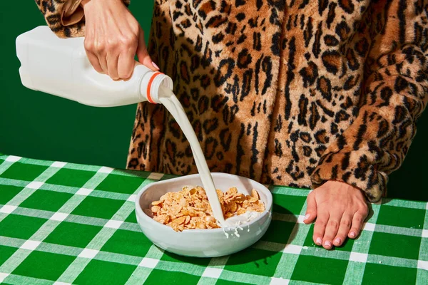女人把牛奶倒入盘子 用玉米片铺在绿色桌布上 该吃早饭了复古风格的内饰 食品流行艺术摄影 互补的颜色 文字的复制空间 — 图库照片