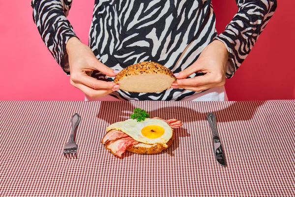 ベーグル 目玉焼き ベーコンをピンク色の背景でおいしいアメリカの朝食を作る女性 ヴィンテージ レトロスタイルのインテリア フードポップアート写真 補完的な色 テキストのコピースペース — ストック写真