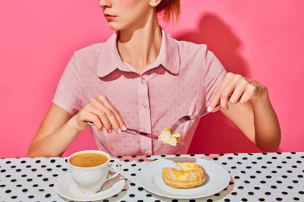 Stock image Young woman having delicious breakfast with donut and coffee over pink background. Yummy. Vintage, retro style interior. Food pop art photography. Complementary colors. Copy space for ad, text