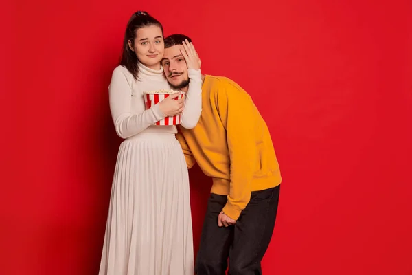 一对快乐的年轻夫妇的画像 男人和女人 在红色的背景下显得孤立无援 一起看恐怖片 爱的概念 情人节 生活方式 — 图库照片