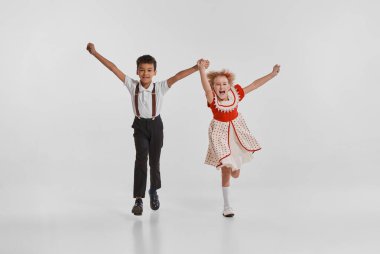 Güzel küçük çocukların portresi, gri arka planda izole edilmiş klasik elbiseli kız ve erkek. Okula dönelim. Çocukluk kavramı, yaratıcılık, eski moda, arkadaşlık, sanat